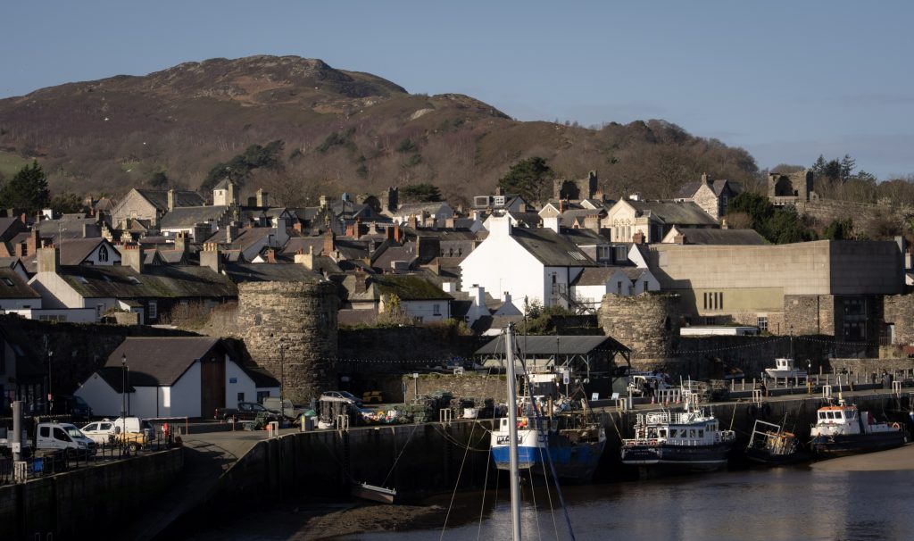 Conwy Harbour in Snowdonia North Wales with boats, town rooftops, historic walls, and hillside backdrop