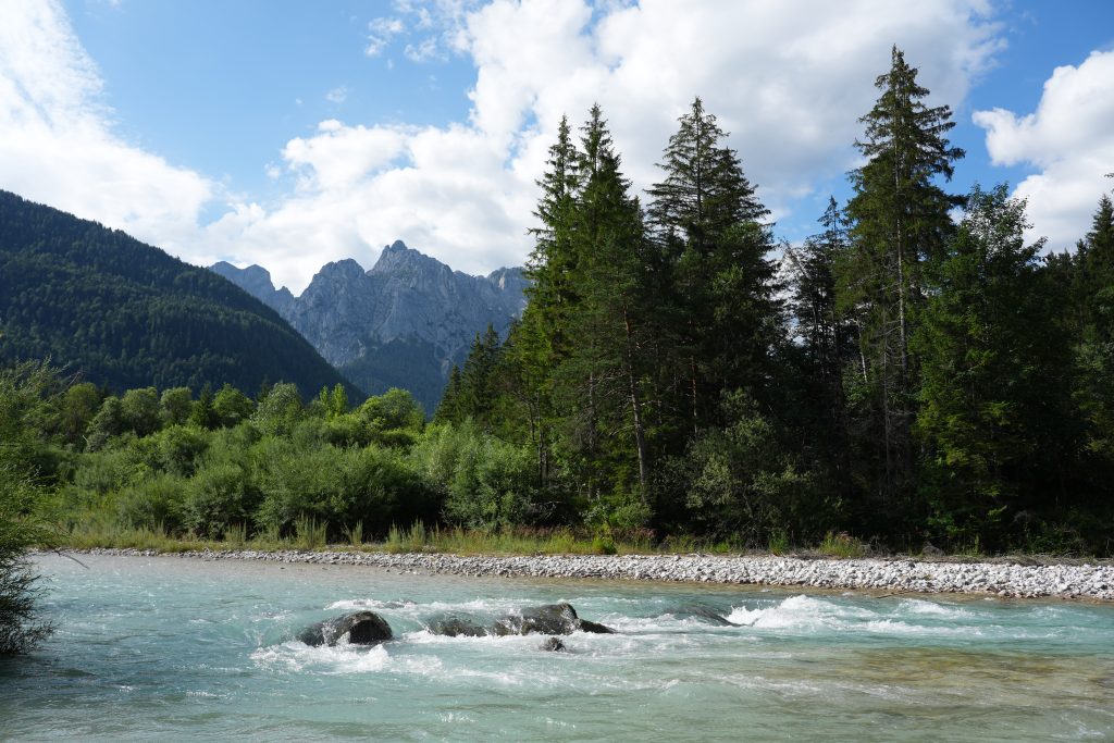 Turquoise Isar River flowing past trees beneath the mountains near Isarhorn campsite