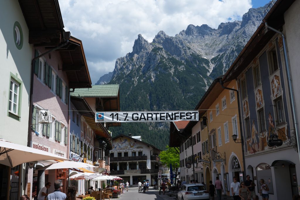 Festival banner hanging across a Mittenwald street with Alpine mountains behind the buildings